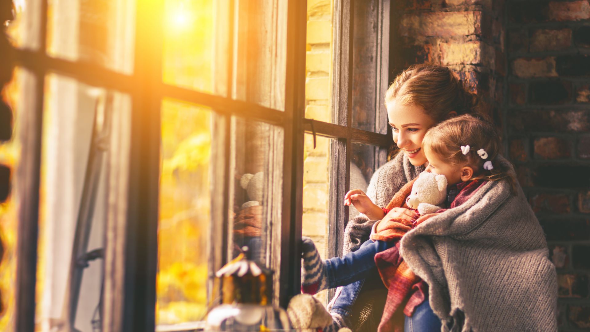 Woman looking out of a window with a child in her arms